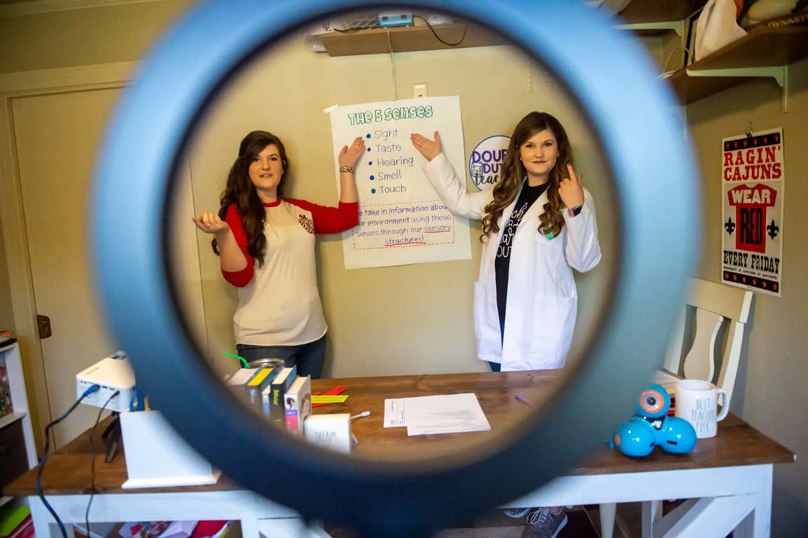 Two girls standing other side of a ring light